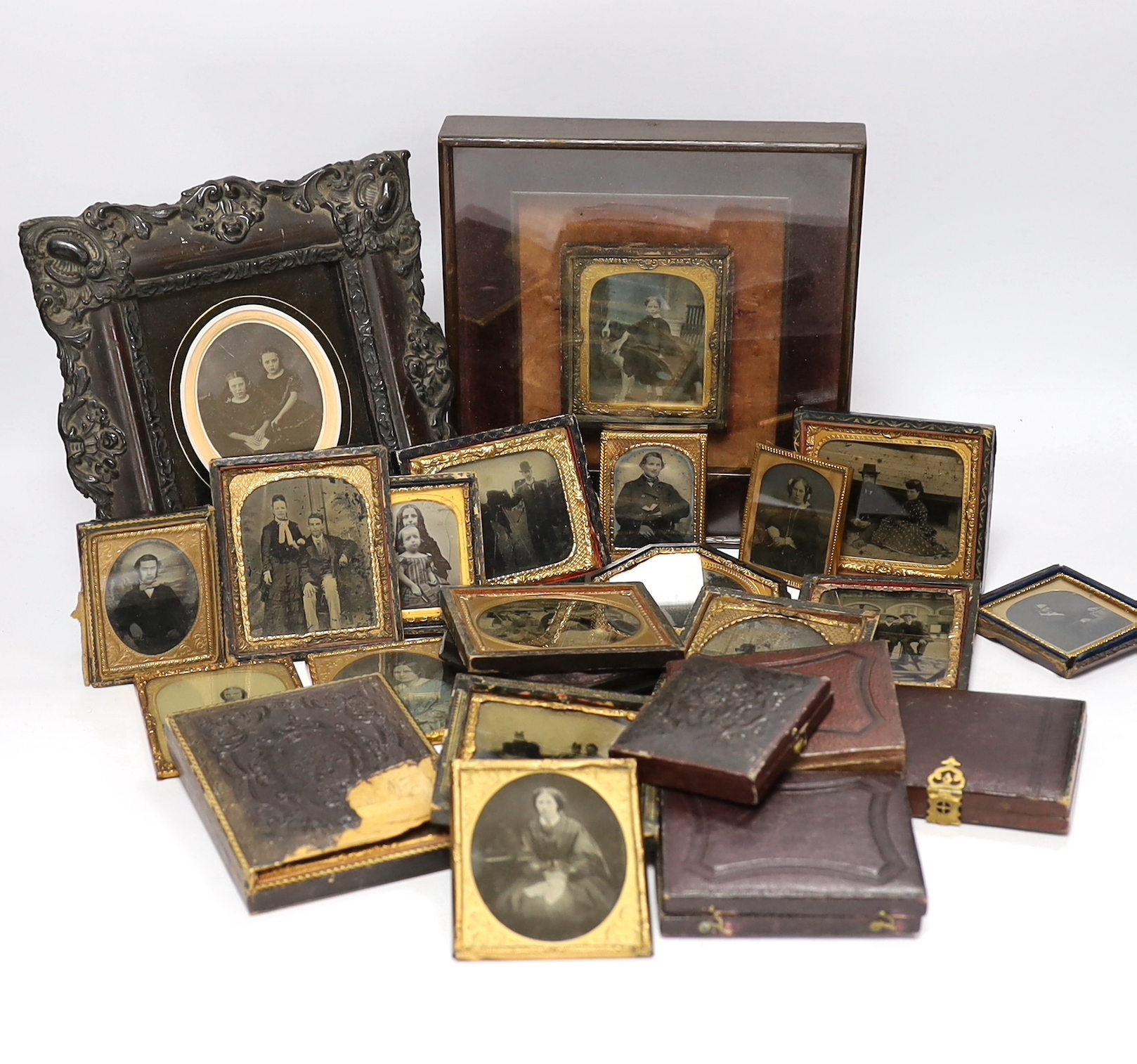 A collection of mid 19th century ambrotype portrait photographs, all mounted in brass etc frames, some in decorative cases, two examples framed (25)